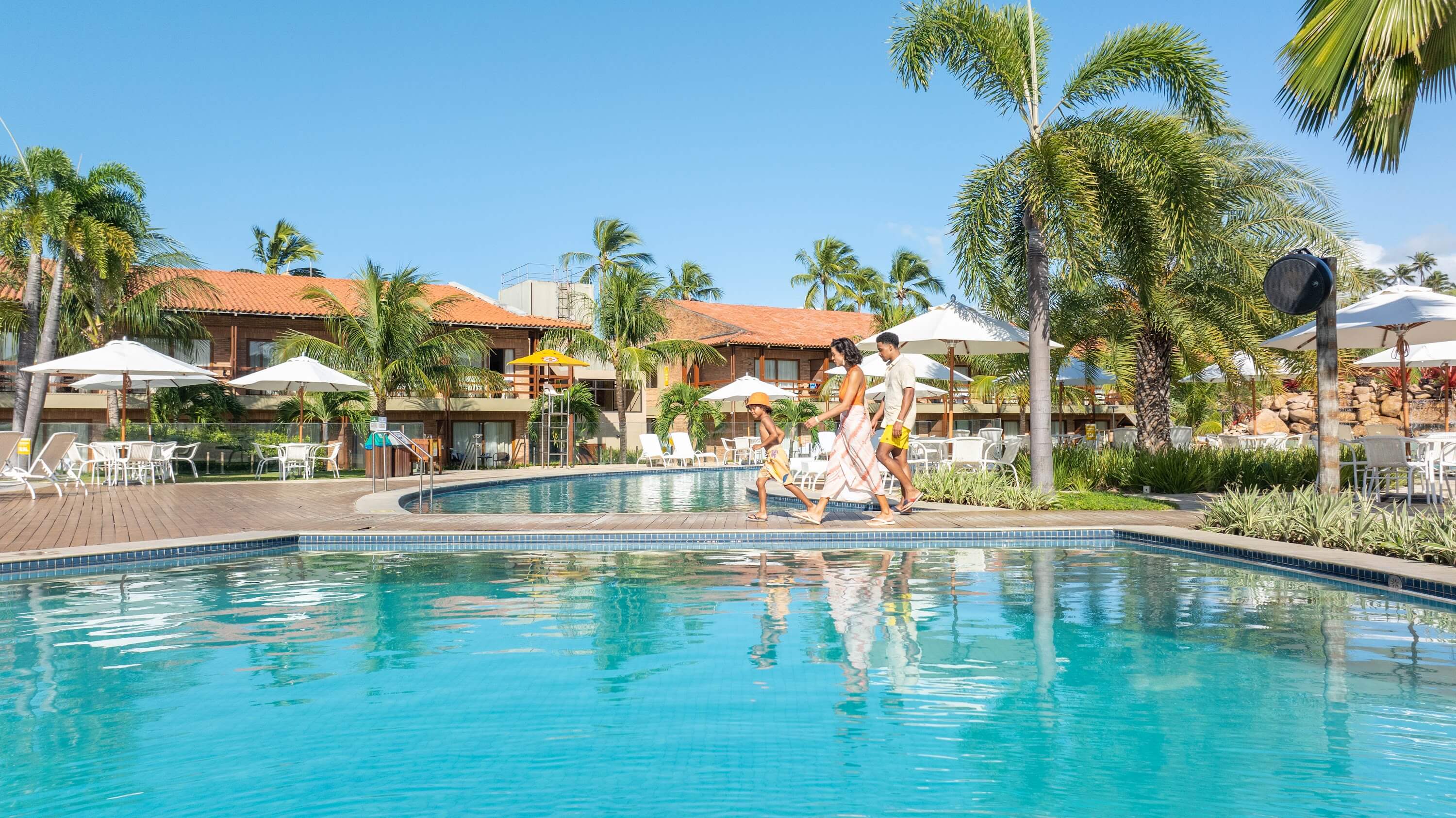 Família caminhando ao lado de piscina principal do Salinas Maragogi All Inclusive Resort.